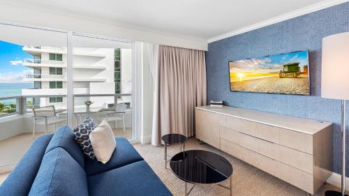 een woonkamer met een blauwe bank en een groot raam bij Fontainebleau Ocean View Private Residence -90103 in Miami Beach