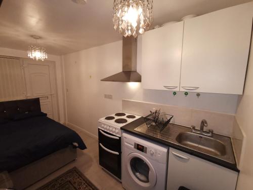 uma pequena cozinha com um lavatório e um fogão em Argyll Studio Apartment - Luton Airport em Luton