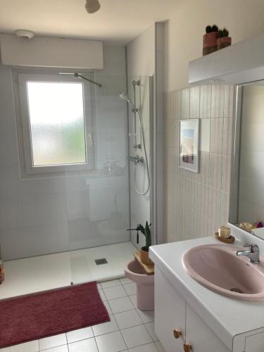 y baño con lavabo rosa y ducha. en Maison familiale dans une rue paisible, en Gouville-sur-Mer
