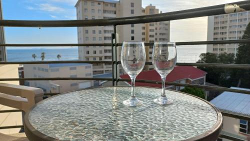 two wine glasses sitting on a table on a balcony at Nautica Strand in Cape Town
