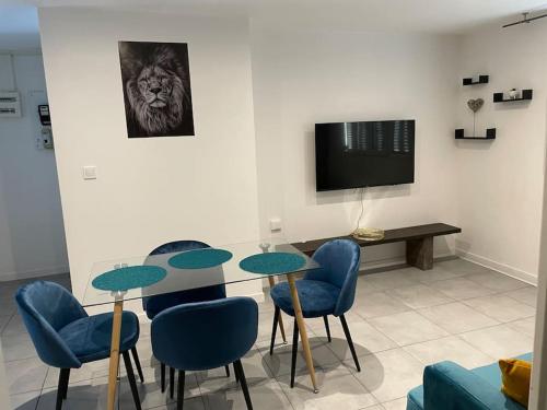 a dining room with a table and chairs and a tv at Logement Rénové - Une Expérience Unique - Wifi Gratuit in Grenoble