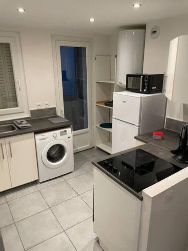 une cuisine avec des armoires blanches et une machine à laver dans l'établissement Logement Rénové - Une Expérience Unique - Wifi Gratuit, à Grenoble