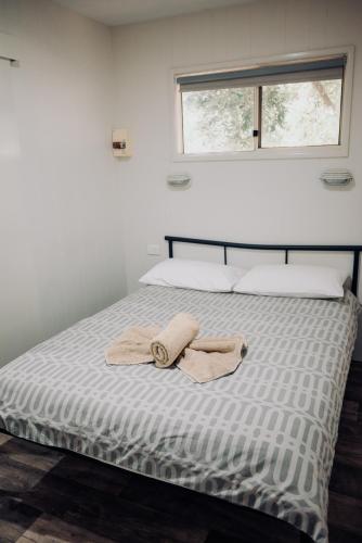 a bed with two towels on it with a window at West View Caravanpark in Dubbo