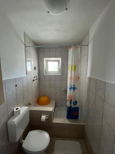 a bathroom with a toilet and a tub and a shower curtain at Apartments Edina in Pag