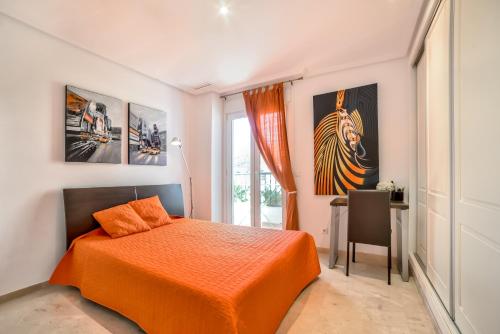 Schlafzimmer mit einem orangenen Bett und einem Schreibtisch in der Unterkunft OASIS BEACH MASCARAT in Altea