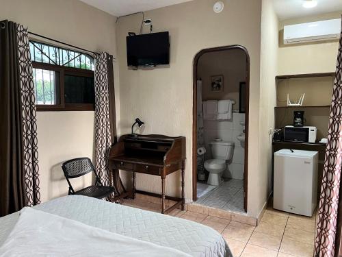 a bedroom with a bed and a desk and a bathroom at El Mesón de los Abuelitos in Retalhuleu