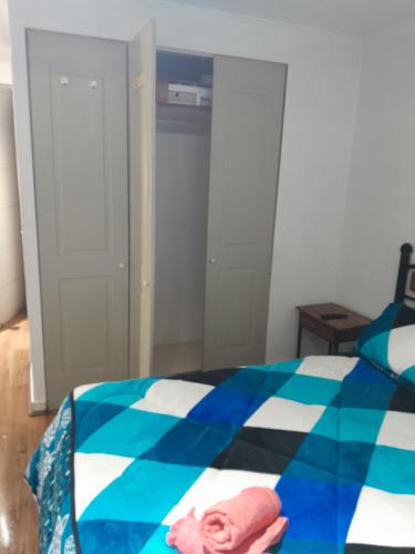 a bedroom with a blue and white comforter on a bed at Apartamento tipo estudio acogedor entre metro católica y baquedanono in Santiago