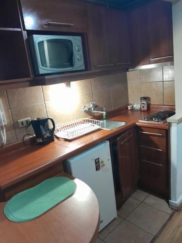 a small kitchen with a sink and a microwave at Apartamento tipo estudio acogedor entre metro católica y baquedanono in Santiago