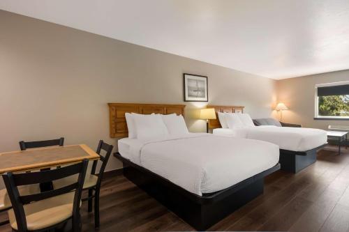 a hotel room with two beds and a table at SureStay Plus Hotel by Best Western Rexburg in Rexburg