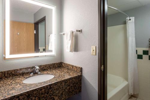 a bathroom with a sink and a mirror and a tub at Black Beach Inn by GrandStay in Silver Bay