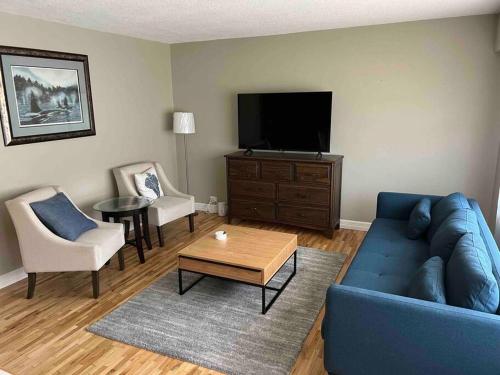 ein Wohnzimmer mit einem blauen Sofa und einem TV in der Unterkunft Cozy Capitol Hill Bungalow - 3BD/2BA Retreat in Burnaby