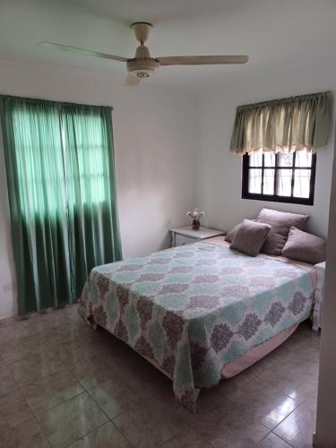 a bedroom with a large bed with green curtains at Guridys Room for Rent ! in Los Tres Ojos de Agua