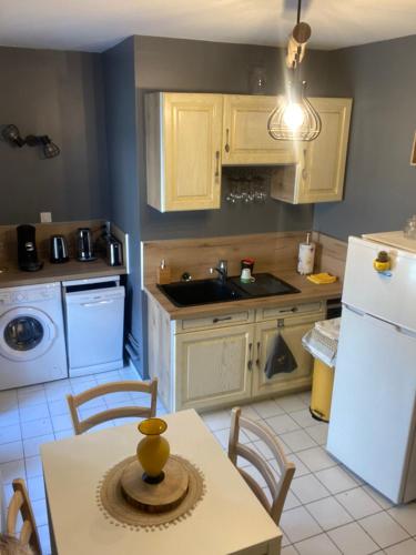 a kitchen with a table and a white refrigerator at La Cigale Ardéchoise in Labégude
