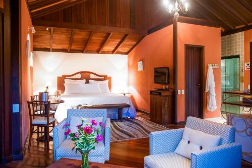 a bedroom with a bed and two chairs and a table at Maua Brasil Hotelaria in Visconde De Maua