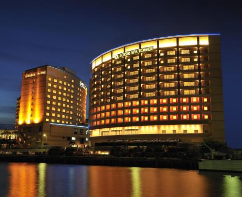 een verlicht hotelgebouw naast een waterlichaam bij Loisir Spa Tower Naha in Naha