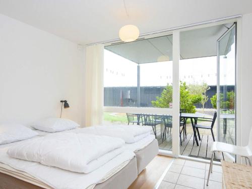 ein weißes Schlafzimmer mit 2 Betten und einem Balkon in der Unterkunft Holiday home Grenaa XLIX in Grenå