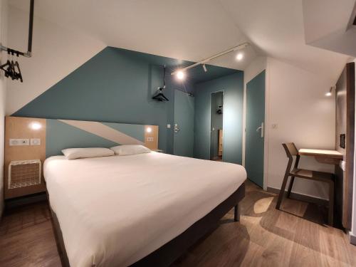 um quarto com uma cama grande e uma parede azul em ibis budget Chambourcy Saint Germain em Chambourcy
