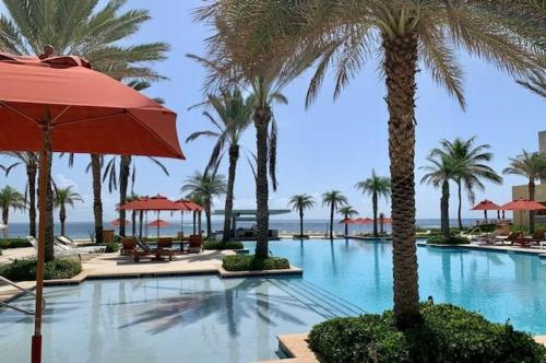 uma piscina com palmeiras e um guarda-sol em Beachfront 3 Bedroom Villa em Dawn Beach