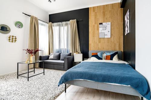 a bedroom with a blue bed and a couch at CityHeart Studio in Bucharest