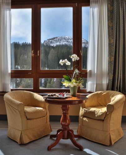 a room with two chairs and a table and a window at TH Madonna di Campiglio | Golf Hotel in Madonna di Campiglio