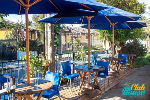 CLUB HOUSE BY CONCON في كونكون: مجموعة طاولات وكراسي مع مظلات زرقاء