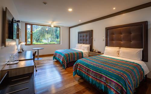 a hotel room with two beds and a desk at San Jose de Puembo Quito Airport, an Ascend Collection Hotel in Puembo