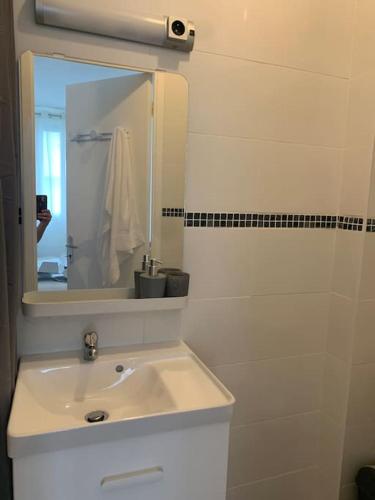 une salle de bain blanche avec un lavabo et un miroir dans l'établissement Studio en plein centre ville, à Quimper