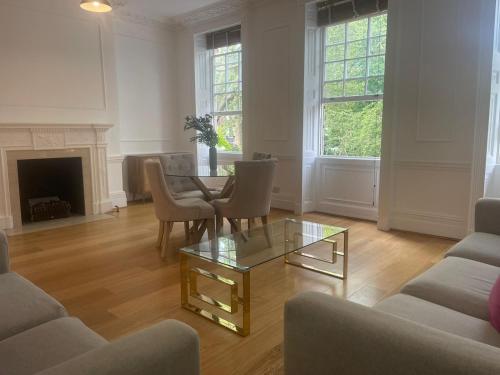 sala de estar con mesa, sillas y chimenea en Kensington Luxury Apartments, en Londres