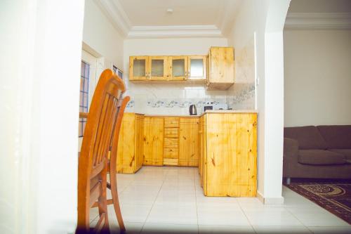 cocina con armarios de madera, silla y sofá en SeneGambia Beach Apartment en Sarin NʼJaga