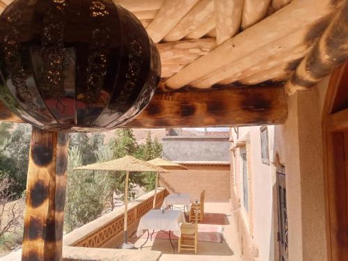 a balcony with a table and chairs and an umbrella at Dar Mezyana Dades in Aït Idaïr