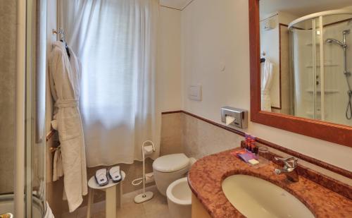 a bathroom with a sink and a toilet and a mirror at TH Madonna di Campiglio | Golf Hotel in Madonna di Campiglio