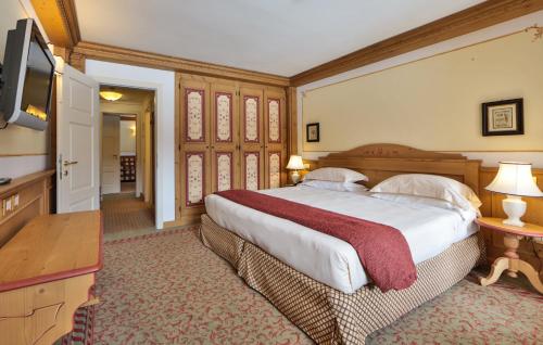 a bedroom with a large bed and a flat screen tv at TH Madonna di Campiglio | Golf Hotel in Madonna di Campiglio