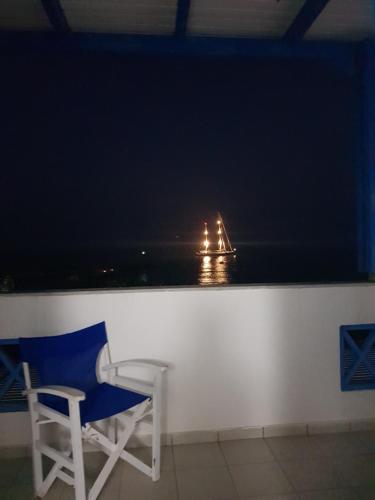 a chair sitting in front of a window with a boat in the water at Rodothea and Adams on the Beach, Santorini in Monolithos