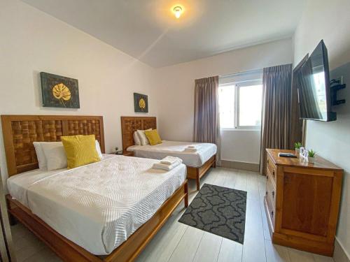 Un dormitorio con dos camas y un televisor. en Acceso a la playa 2 hab 3 camas 6 pax bella piscin, en Punta Cana