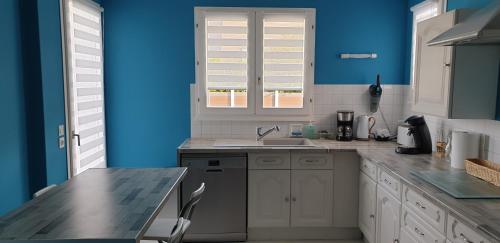 d'une cuisine avec des murs bleus, un évier et un comptoir. dans l'établissement Le Paradis des Fleurs, au Tréport