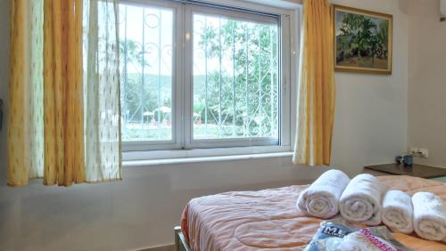 a bedroom with a window with towels on a bed at Villa Vivere in Corfu Town