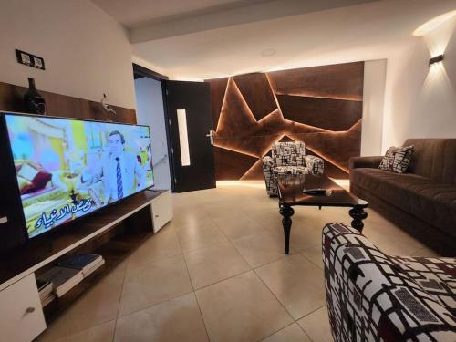 ein Wohnzimmer mit einem Sofa und einem großen Flachbild-TV in der Unterkunft Appartement Idéal : Proximité, Confort et Élégance in Tétouan