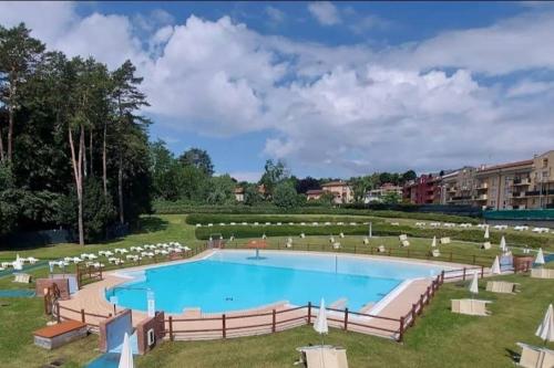 uma grande piscina com cadeiras brancas num parque em Appartamento stupendo sul, lago Como em Villa Guardia