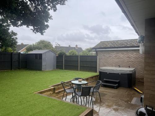 a backyard with a table and chairs and a hot tub at Immaculate 2-Bed Bungalow in Snettisham in Snettisham