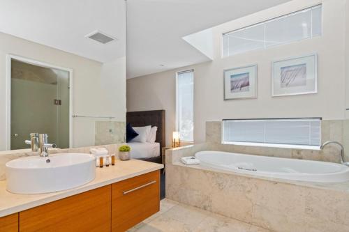 a bathroom with a large tub and a sink at Beachside Bliss 1 Bedroom Park View Villa in Mandurah