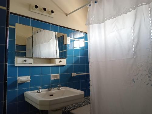 een blauw betegelde badkamer met een wastafel en een spiegel bij El balcón de la esquina in Maipú