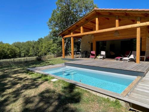 une maison avec une piscine et une terrasse en bois dans l'établissement Gîte confortable avec piscine privée et jardin clos en Dordogne - FR-1-616-319, à Castelnaud-la-Chapelle