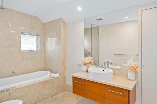 a bathroom with a sink and a tub and a toilet at Beachside Bliss 2 Bedroom Family Villa in Mandurah