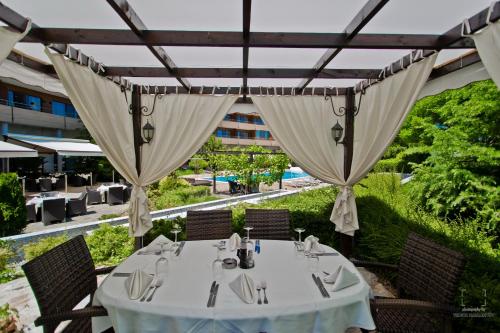 a dining table under a pergola at a restaurant at Grand Hotel Pomorie - Medical spa in Pomorie