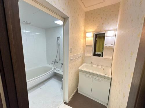 a bathroom with a tub and a sink and a mirror at City Villa Rアネックス in Osaka