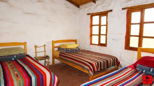 two beds in a room with two windows at Samary -wasi maragua in Estancia Chaunaca