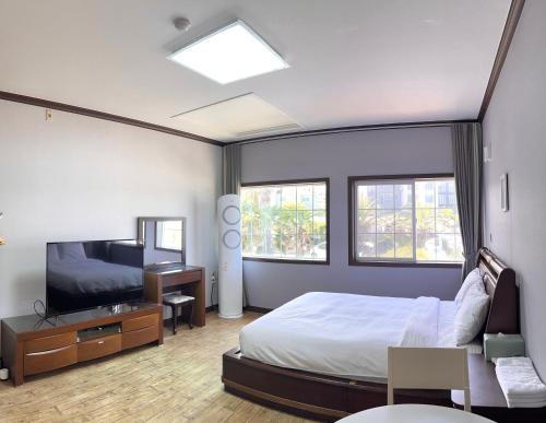 een slaapkamer met een groot bed en een televisie bij Grim Resort in Jeju-stad