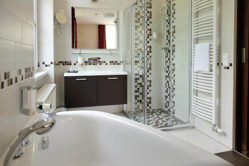 a bathroom with a tub and a shower and a sink at Corner Hotel & Kávéház in Dunaújváros