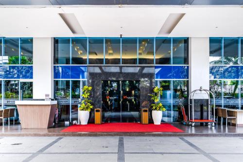 a lobby of a building with a red carpet and plants at Swiss-Belinn Malang in Malang