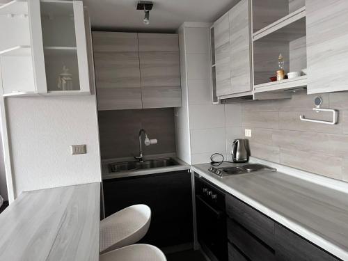 a kitchen with white cabinets and a sink and chairs at Bideluxe Apart Hotel in Los Ángeles